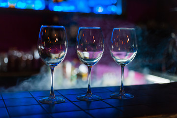 Two empty wine glasses arranged on the counter before the party to start in restaurant or bar with smoke 