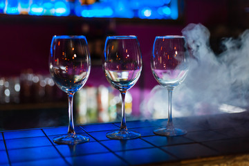 Two empty wine glasses arranged on the counter before the party to start in restaurant or bar with smoke 