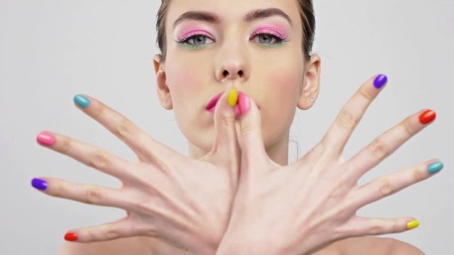 Beautiful woman with bright vivid makeup. Sexy adult girl with colorful nails on the hands.