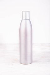 A bottle opaque with pink shampoo inside on a white background