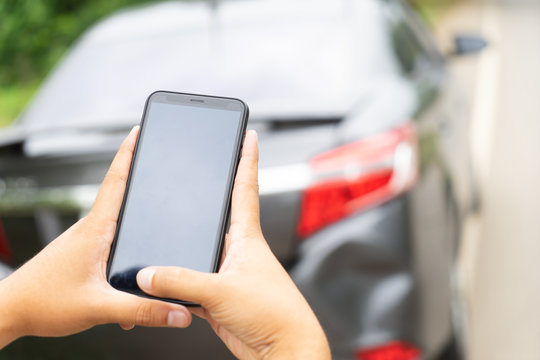Man Hand Taking Photo Of Car Accident Through Smartphone, close up..Insurance agent using smart phone to take a photo photographing vehicle of damage car crash.