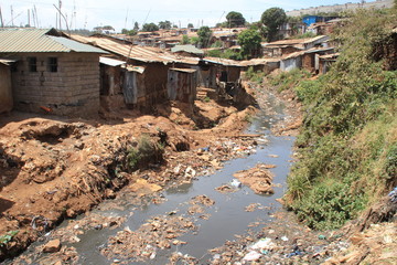 Kibera, Nairobi, Kenya - February 13, 2015: Huge heaps of garbage and a dirty river in the slums of Nairobi - one of the poorest places in Africa - obrazy, fototapety, plakaty