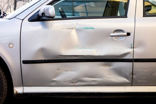Damaged side door on a silver car after a small traffic accident