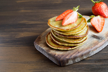 Vegetarian pancakes with ripe strawberries. on a wooden table.