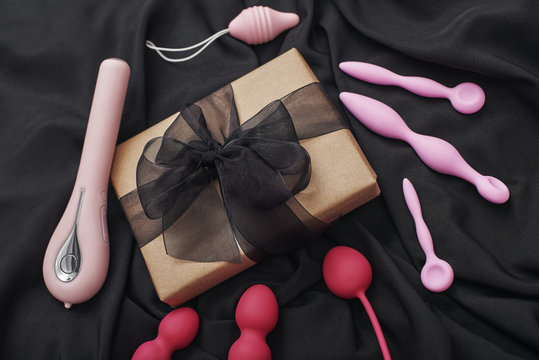 Sex toy gift for the women you love. Composition of colorful various sex toys (dildos, anal plugs, vibrators, kegel balls and others) and gift box