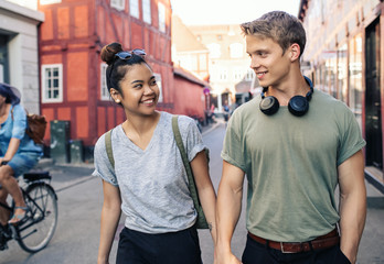 Smiling couple holding hands while walking in the city