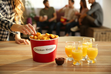 Woman taking tasty nuggets from bucket on table © Pixel-Shot