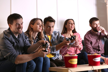 Group of friends eating nuggets while playing video game at home