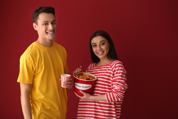 Friends with bucket of nuggets and drink on color background