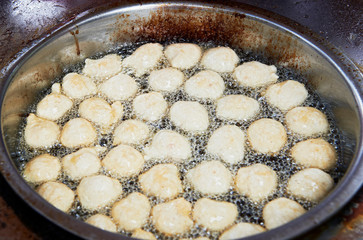 Close-up of fish balls frying in hot oil in a dirty frying pan from a street vendor in the...