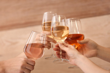 Women clinking glasses with tasty wine on wooden background