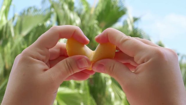 Woman opening chinese fortune cookie with a card inside in slow motion 180fps