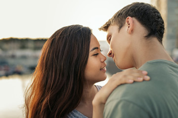 Romantic young couple standing by a harbor about to kiss