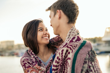 Young couple smiling while wrapped in a blanket together outside