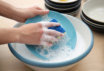 Woman washing plate in kitchen