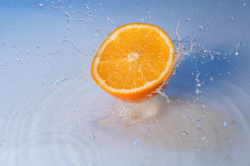 Fototapeta na wymiar Ripe cut orange with water splash on color background
