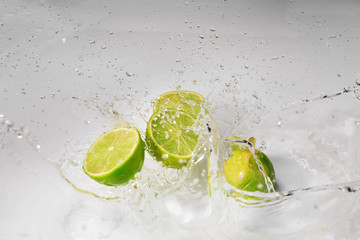 Ripe cut lime with water splash on white background