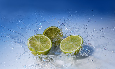 Ripe cut lime with water splash on color background