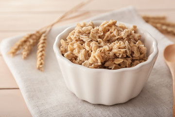 Bowl with tasty oatmeal on table