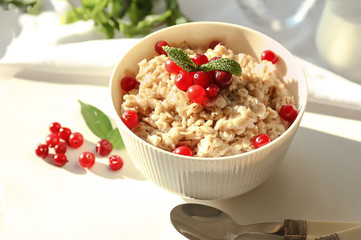 Bowl with tasty oatmeal on white table