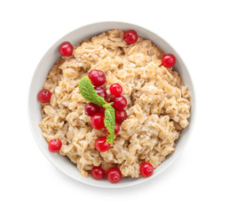 Bowl with tasty oatmeal on white background