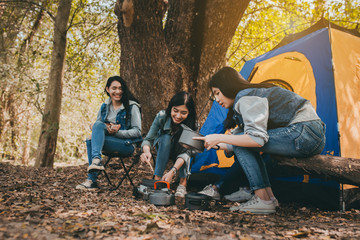 Friends Group of Young Asian women camping and cooking together at forest happy on weekend.