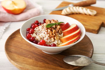 Bowl with tasty oatmeal on table