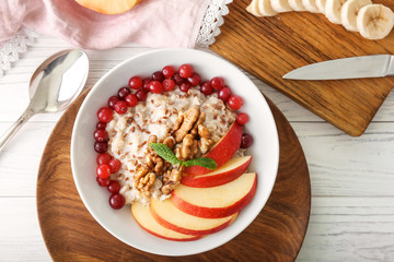 Bowl with tasty oatmeal on white table