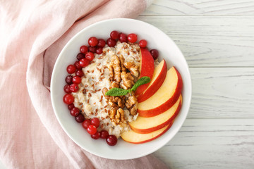 Bowl with tasty oatmeal on white table