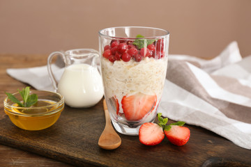 Glass with tasty oatmeal, milk and honey on table