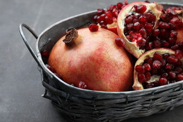 Basket with ripe pomegranates on grey background, closeup