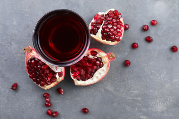 Glass of fresh pomegranate juice on grey background