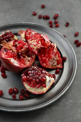 Plate with pieces of ripe pomegranate on table