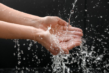 Woman washing hands on dark background