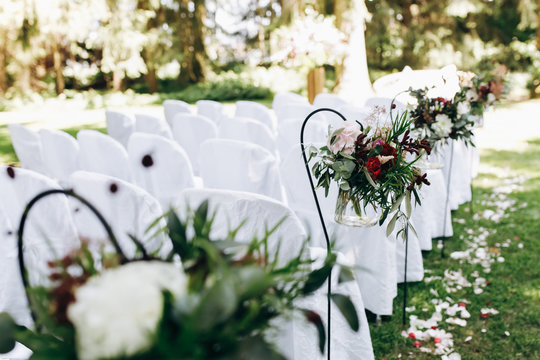 Wedding ceremony. Bouquets of greenery and dark flowers hang on the chair in the garden