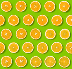 Seamless pattern of orange fruit slices on green background. Flat lay, top view. Food background. .  Pop art design, creative concept. . Creative layout.