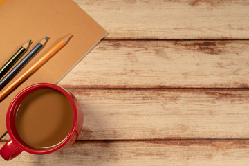 Red Coffee Cup and notebook with  a few colored pencils Flat-lay