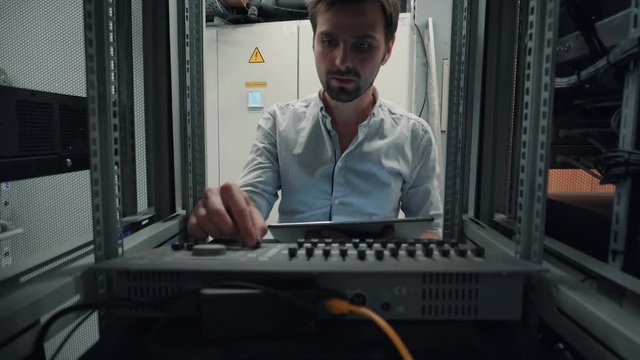 Server IT Engineer In Data Center Server Room.Network Engineer Working Laptop Computer.Server Rack Room Works.Programmer Checks A work Of Server At A Data Center. 