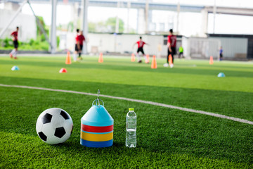 soccer ball, marker cones and bottle water on green artificial turf