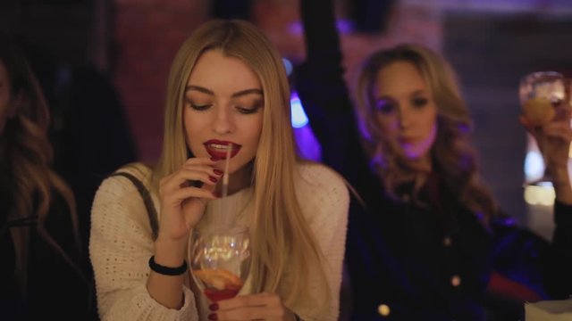 Happy woman drinking alcohol cocktail, celebrating holiday party in the nightclub