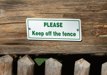 sign says to please keep off fence