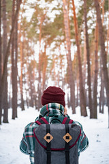 Fototapeta na wymiar Hiking male person in winter forest. Man in checkered winter shirt walking in beautiful snowy woods