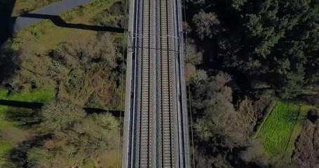 FLYING ABOVE THE TRAIN BRIDGE IN A GREEN VALLEY
