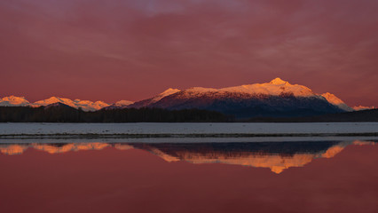 Chilkat Reflection - The Chilkat Mountain Range  in Alpen Glow is reflected in the smooth flowing waters of the Chilkat river at sunrise. Haines, Alaska, 