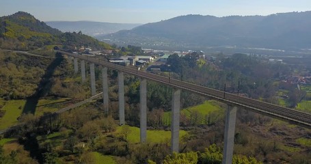 TRAIN BRIDGE IN A GREEN VALLEY WITH FACTORIES, HOUSES AND THE CITY OF OURENSE