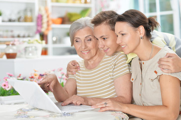 Smiling grandmother,  mother and son using laptop