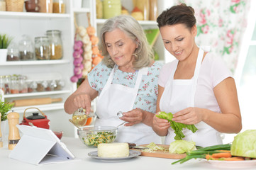 Smiling senior mother and adult daughter cooking together