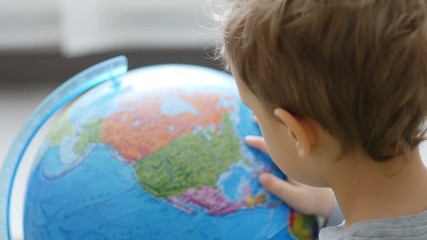 Baby boy plays with globe on floor in room, indoor - Powered by Adobe