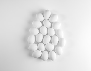 White chicken eggs laid out as large egg on white background.