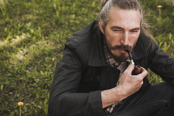 Serious bearded man smoking pipe